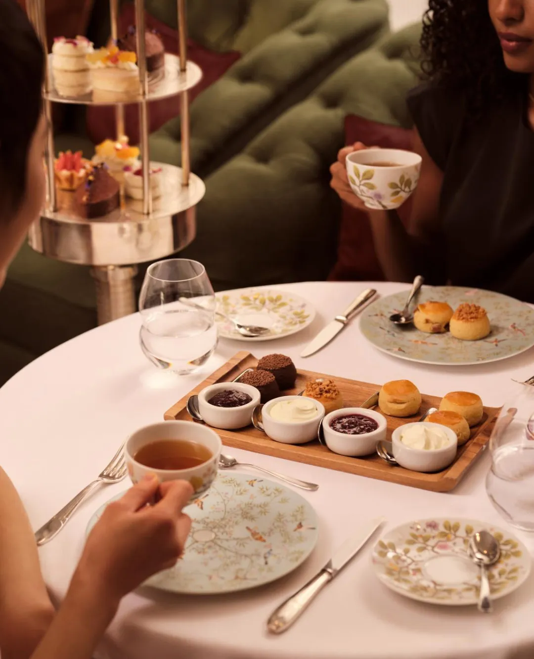 Elegantly arranged afternoon tea service with tiered stand featuring finger sandwiches, scones and petit fours at Jumeirah hotel