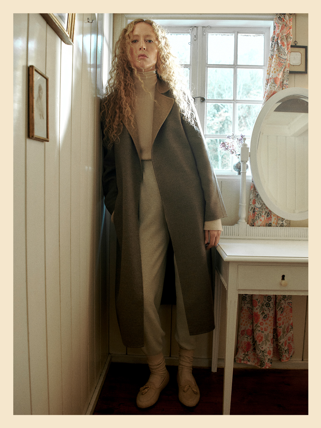 The Francesca coat draped elegantly on a model, photographed in a serene Danish summer residence