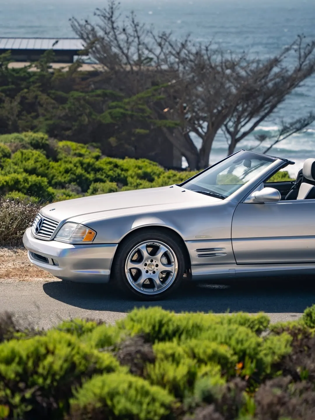 Mercedes-Benz SL 500 classic roadster parked against a scenic coastal backdrop with blue skies