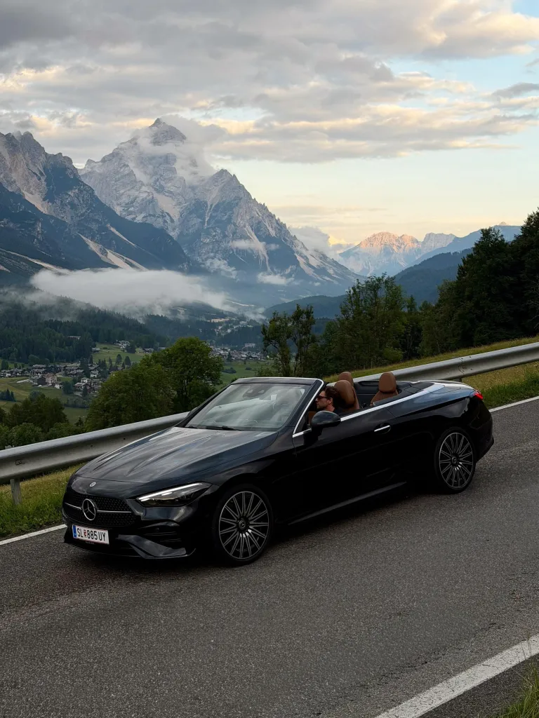 Front three-quarter perspective of the CLE Cabriolet on mountain terrain with expansive valley views