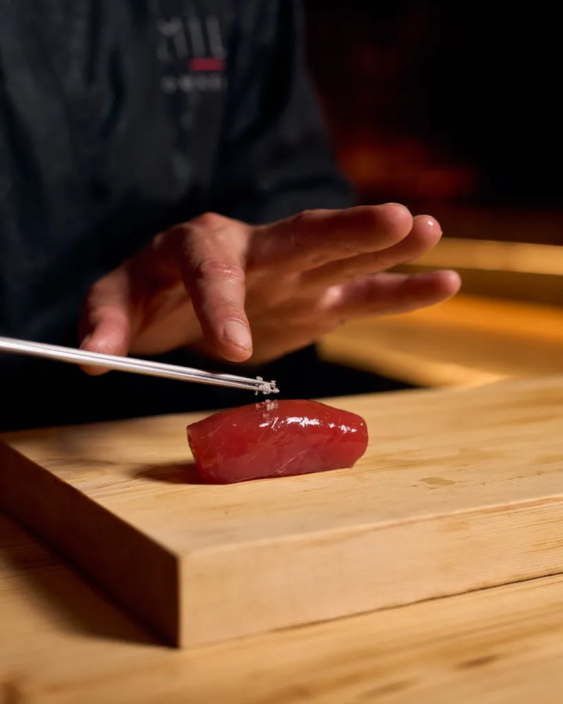 Intimate omakase counter dining experience with chef and diners in close engagement