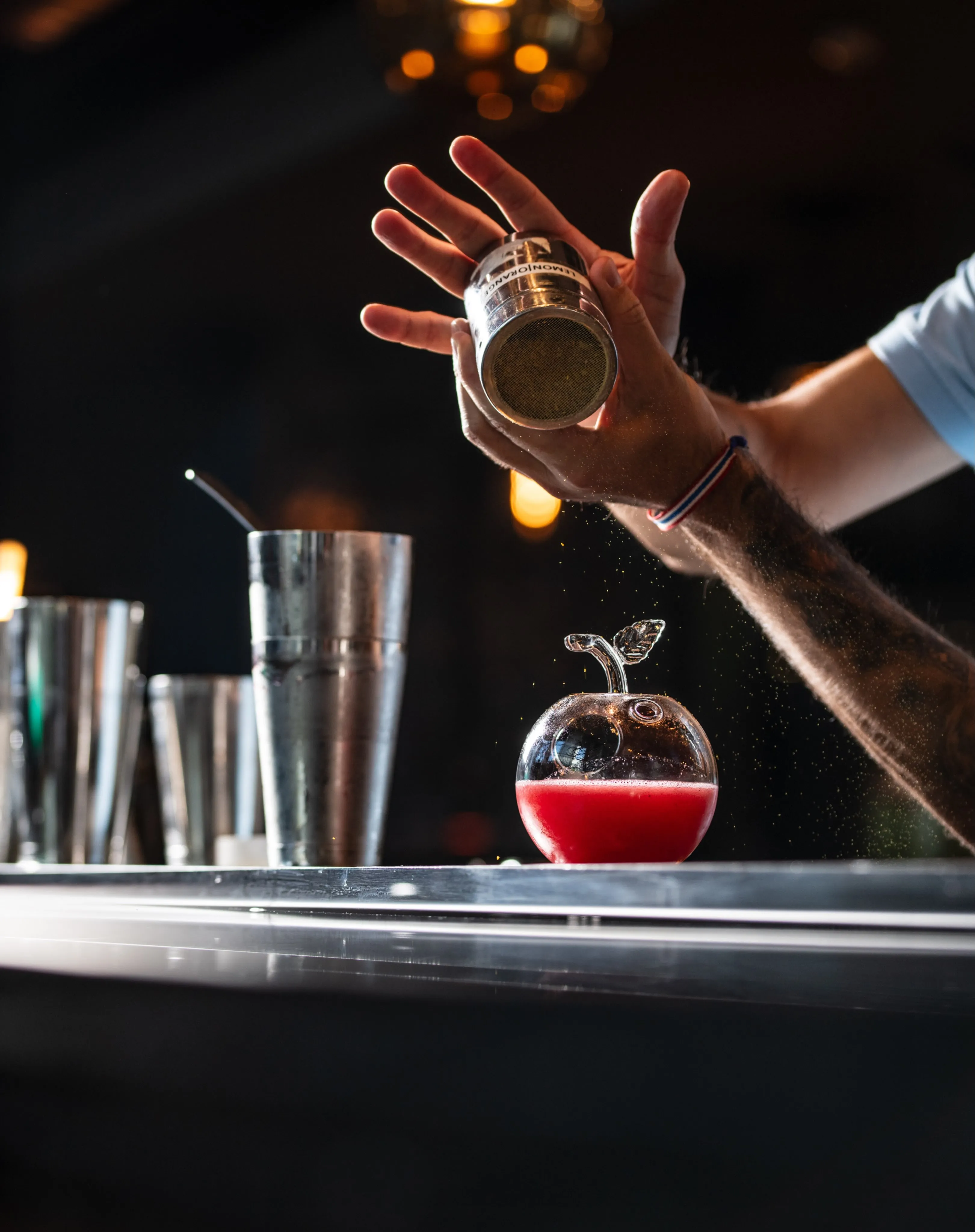 A bartender expertly preparing a cocktail with precise technique and measured concentration at the bar