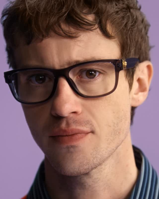 Full-length shot of model positioned against neutral background in architectural eyewear silhouette from the Fall Winter 2026 collection